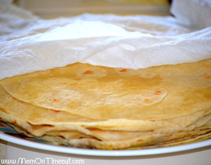 warmed tortillas wrapped in paper towels and on a plate