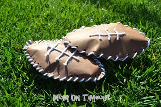 paper footballs made with brown construction paper and yarn on grass