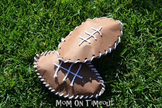 paper footballs made with brown construction paper and yarn on grass