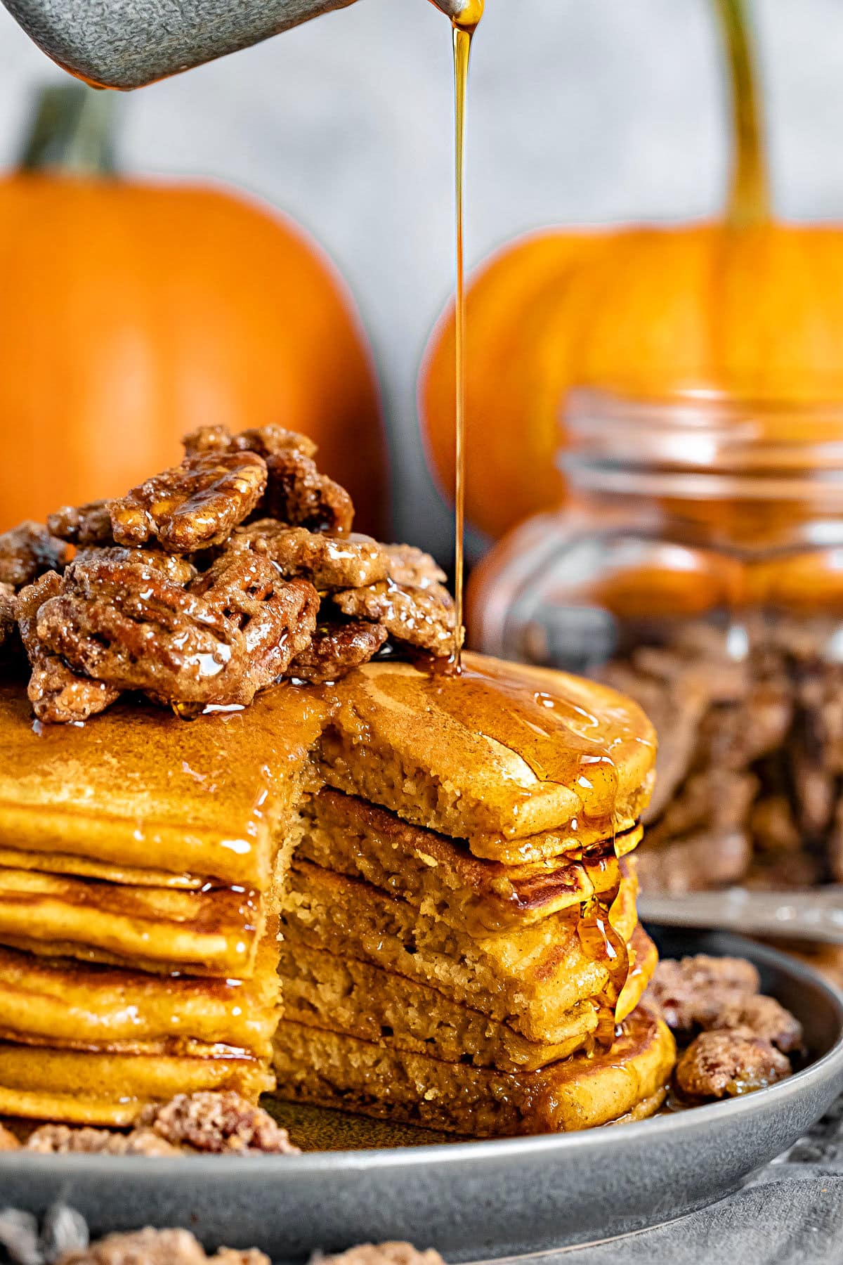 syrup being poured on stack of pumpkin pancakes