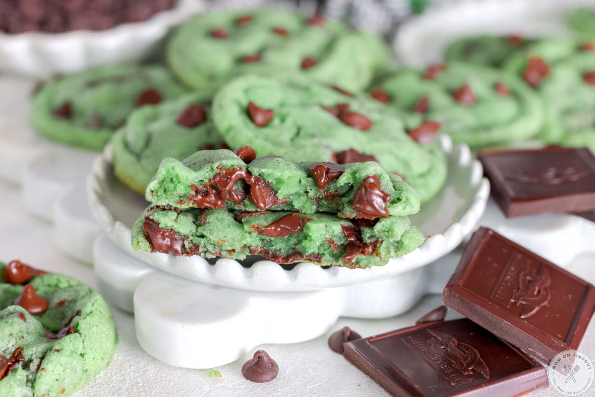 Wide shot of mint chocolate chip cookie cut in half on white plate. 