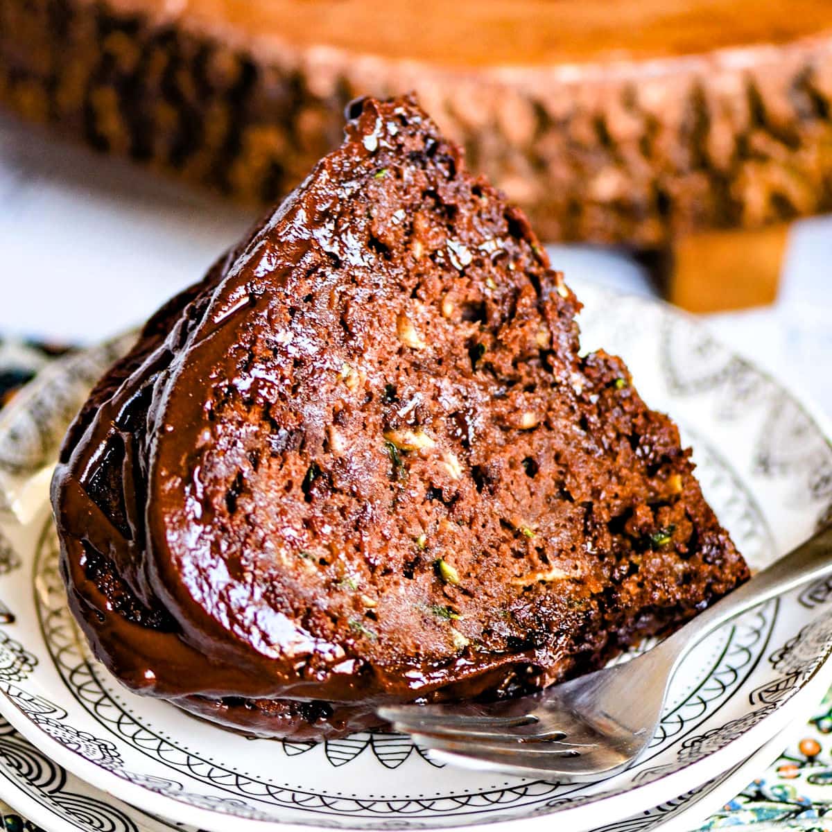 slice of chocolate zucchini cake on white plate.