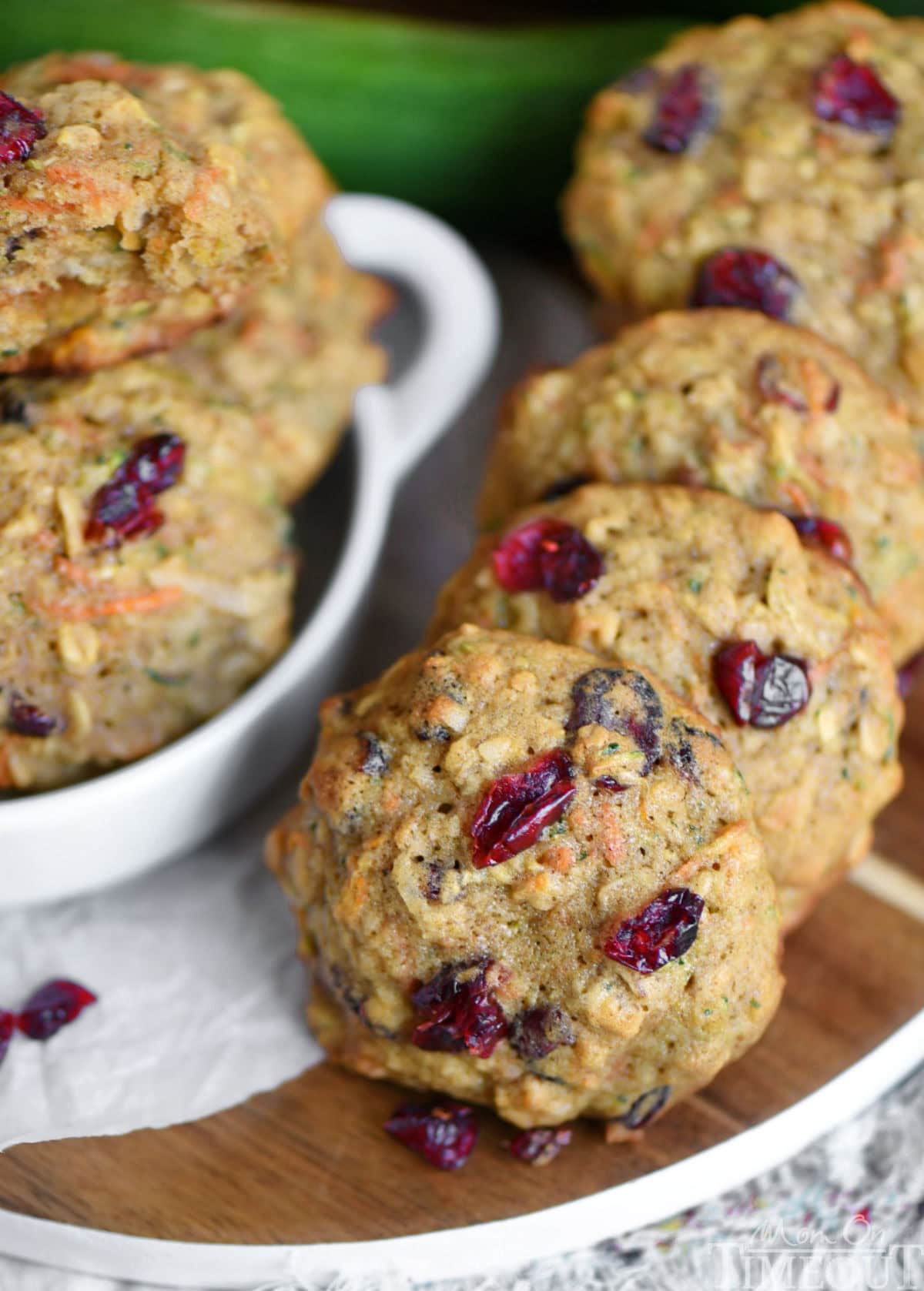 Angled look down at a row of zucchini craisin oatmeal cookies on a round wood board.