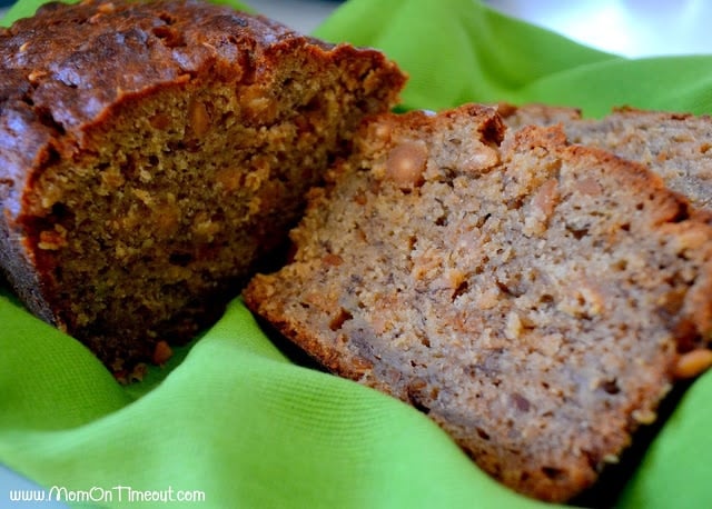 loaf of banana bread with two slices cut on a green towel