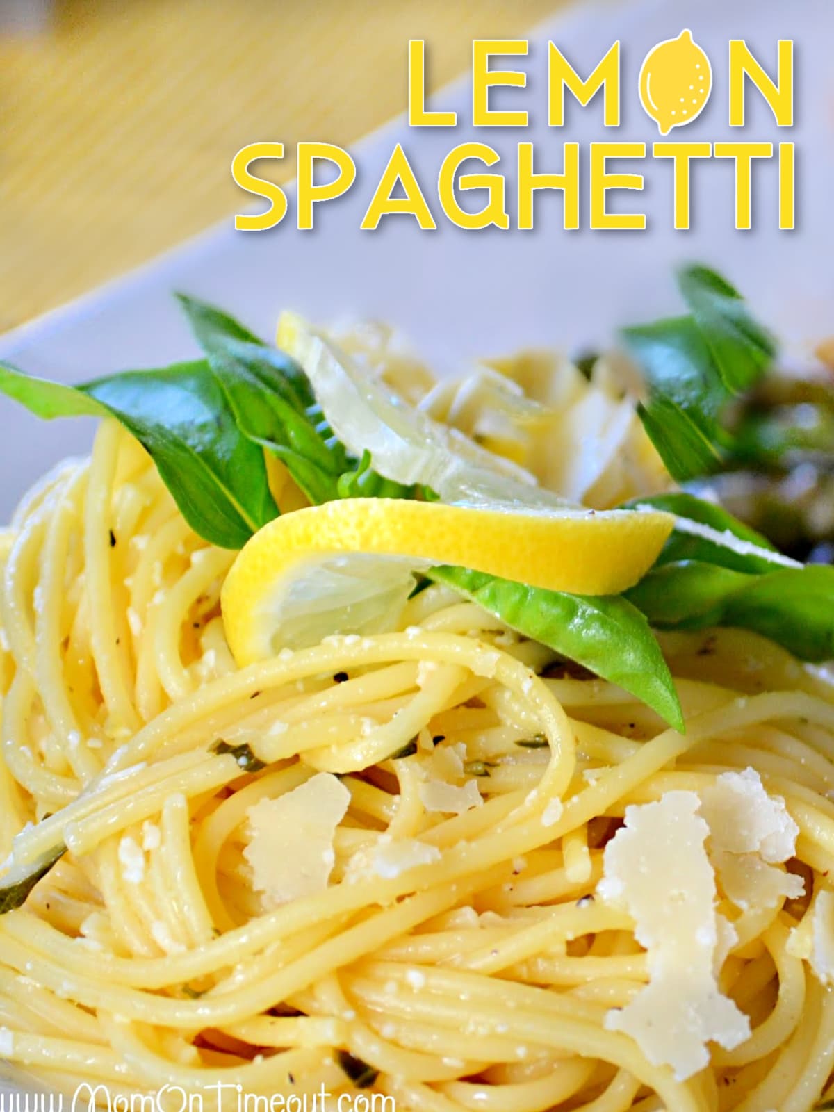 plate of lemon spaghetti with text overlay garnished with parmesan lemon and basil