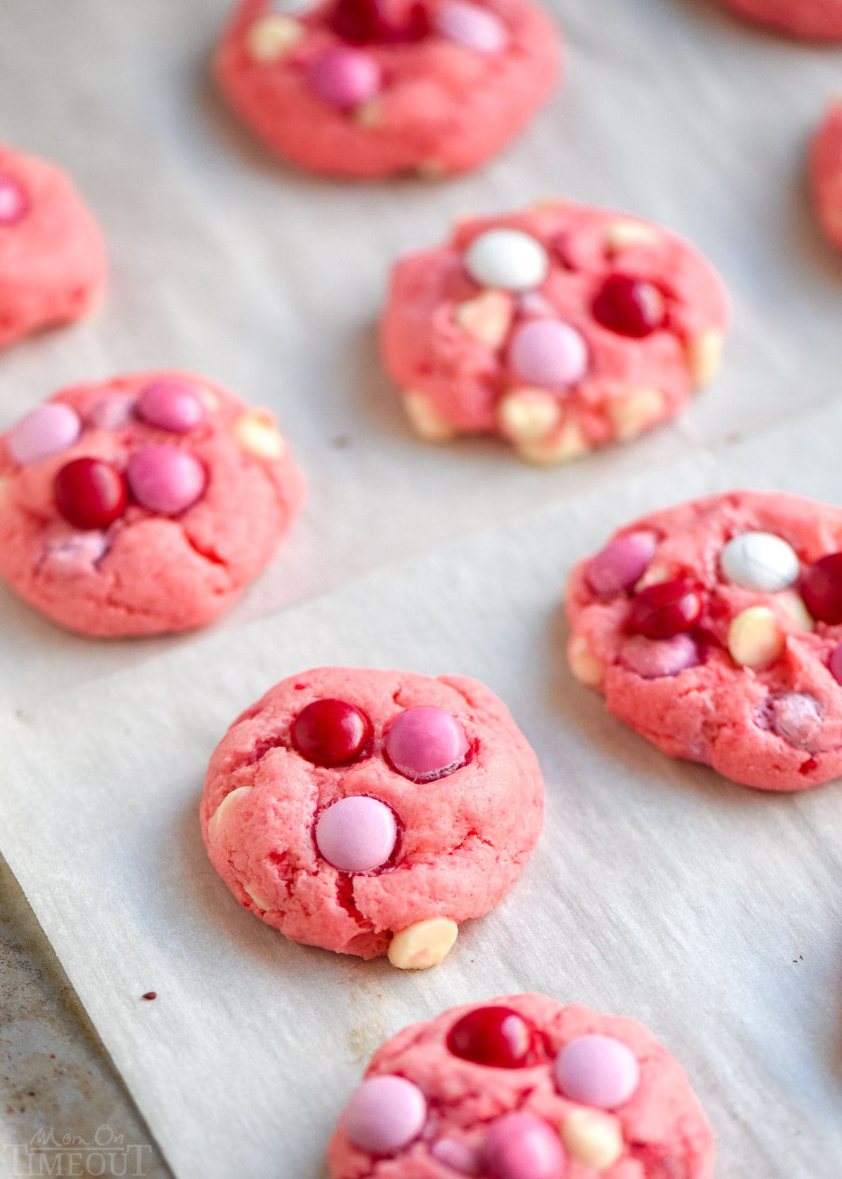 baked strawberry cake mix cookies on a parchment lined cookie sheet.