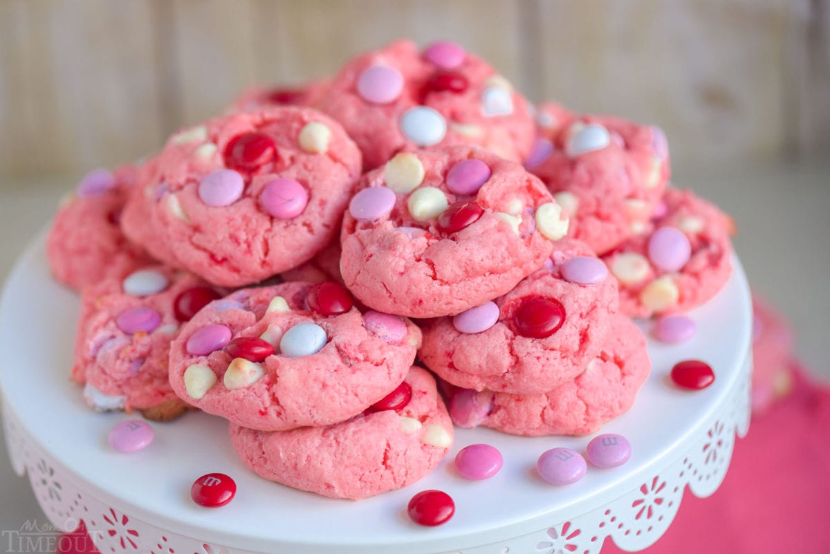 strawberry cake mix cookies made with M and Ms and white chocolate chips piled high on a white metal cake stand.