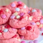 strawberry cake mix cookies made with M and Ms and white chocolate chips piled high on a white metal cake stand.