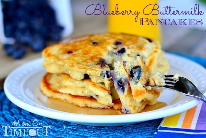 a stack of Blueberry Buttermilk Pancakes on white plate with syrup on a blue placemat