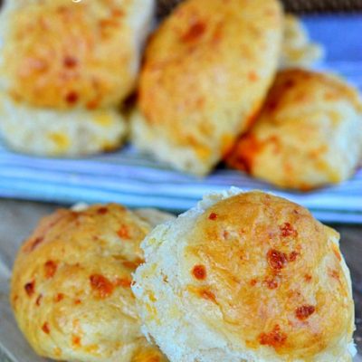 easy cheddar rolls recipe sitting on wood board with more rolls in background