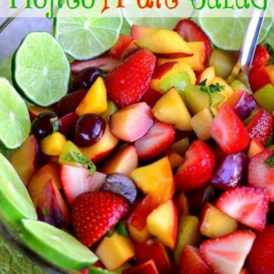 fruit salad in a bowl with lime slices and title overlay at top of image.