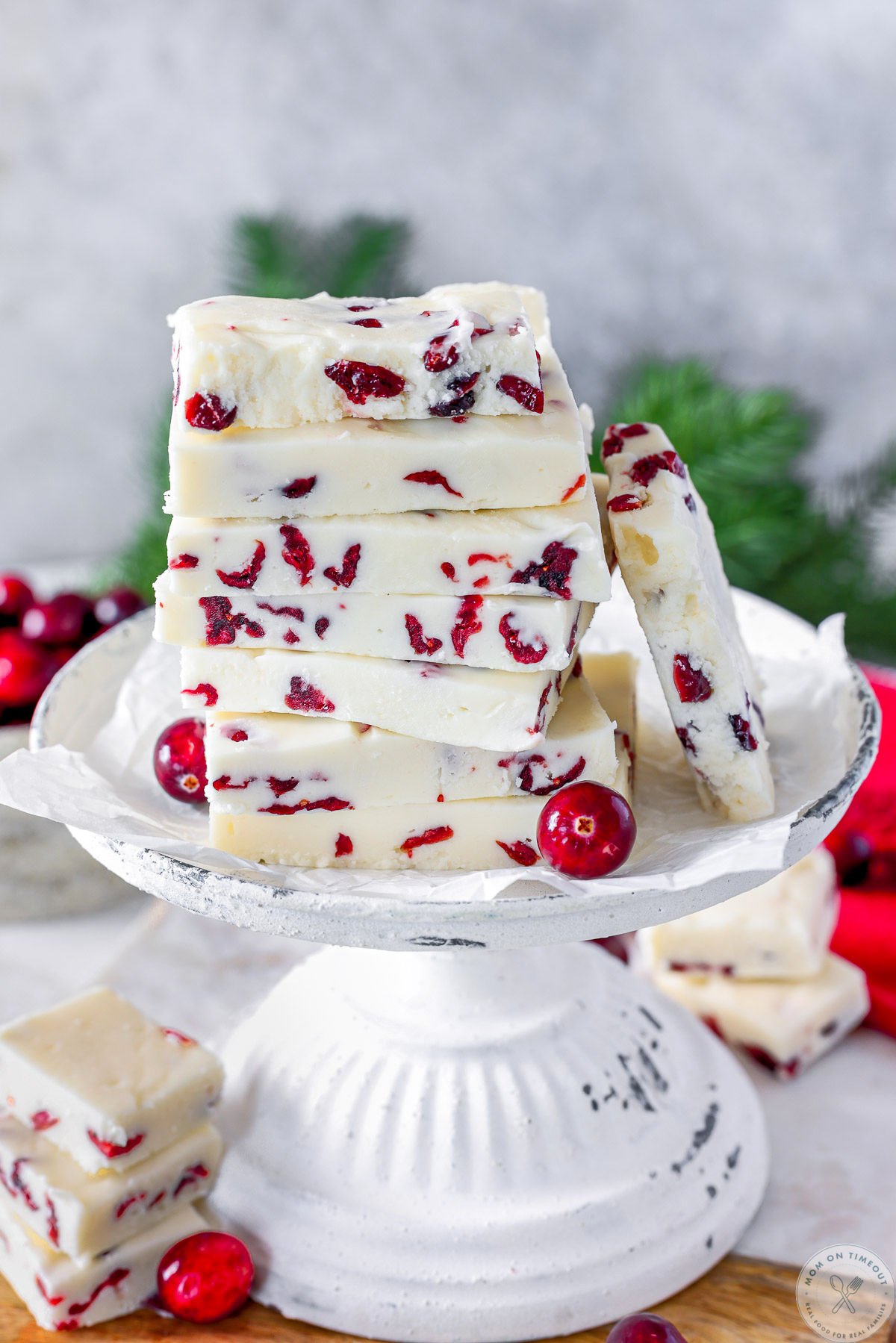 Cranberry fudge cut into rectangles and stacked high on a vintage white stand.