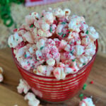 peppermint flavored popcorn in red striped glass bowl made with sprinkles and peppermint candy.