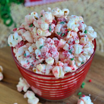 peppermint flavored popcorn in red striped glass bowl made with sprinkles and peppermint candy.