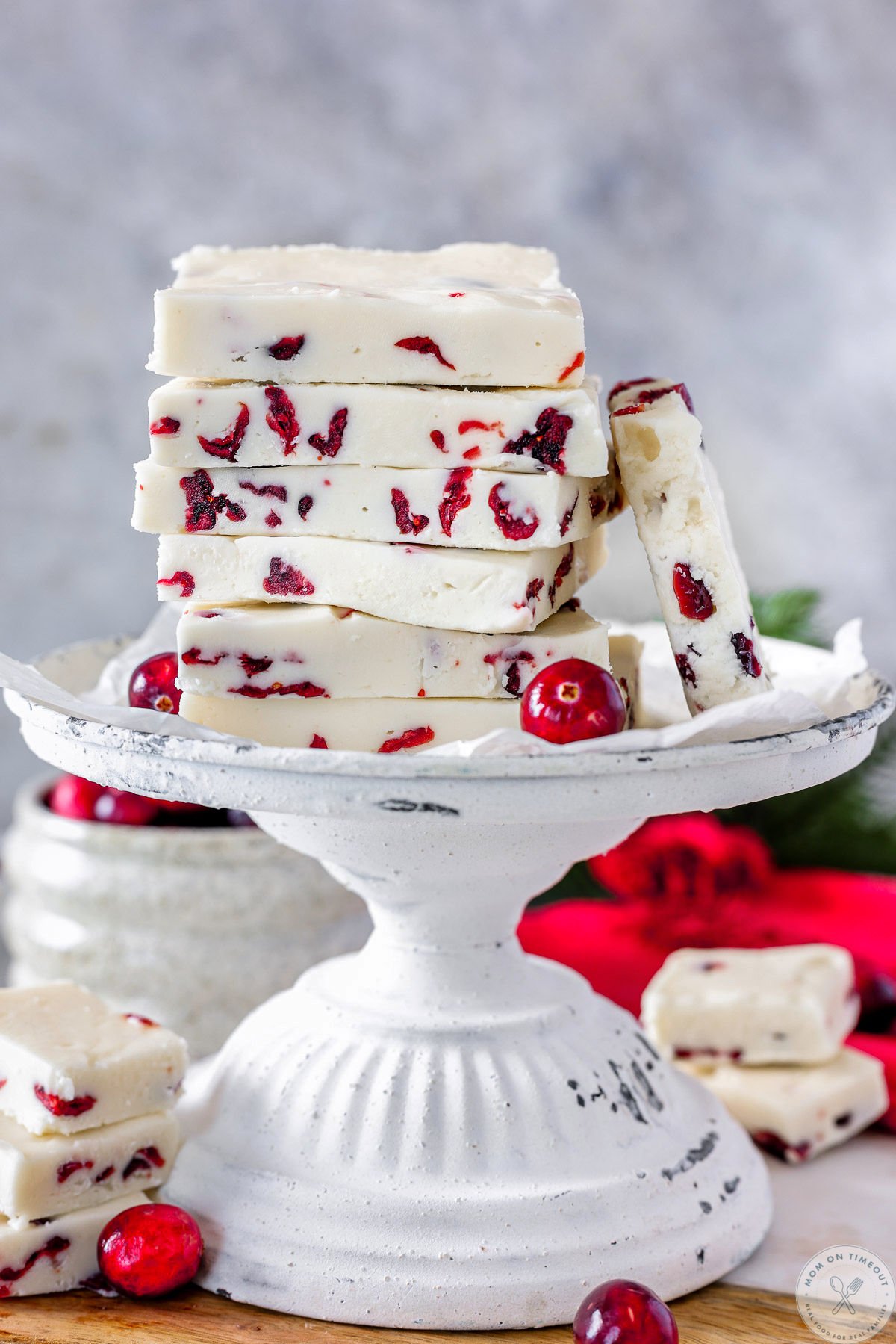 Cranberry fudge cut into rectangles and stacked high on a vintage white stand.