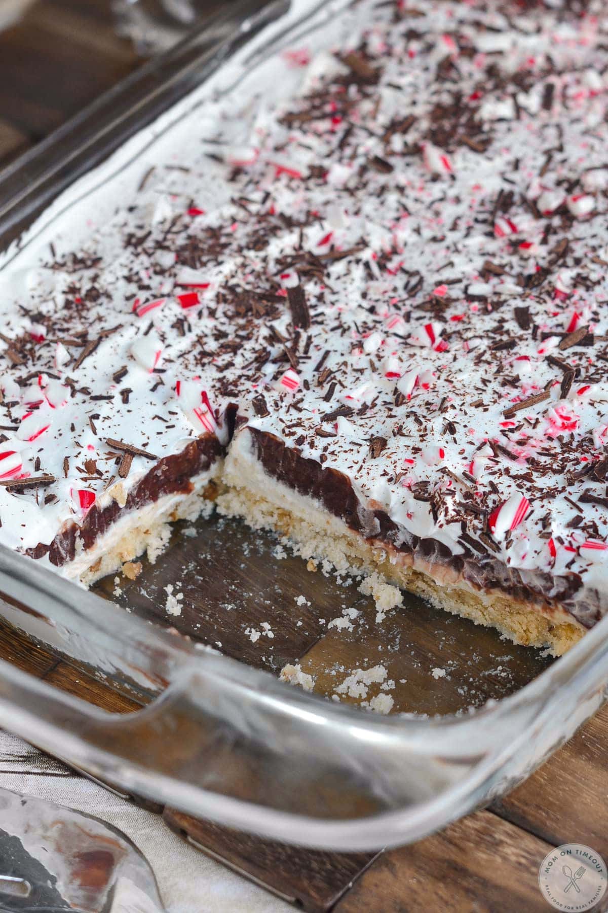 Angled overhead shot of chocolate peppermint lush recipe in glass casserole dish with a few servings removed.