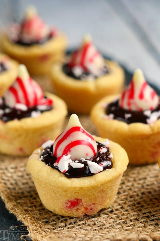 Dark Chocolate Peppermint Sugar Cookie Cups filled with chocolate ganache and topped with Candy Cane Hershey's Kisses. An easy treat that is perfect for the holidays!