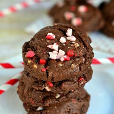 chocolate peppermint cookies stacked on white plate with red and white striped straws scattered about