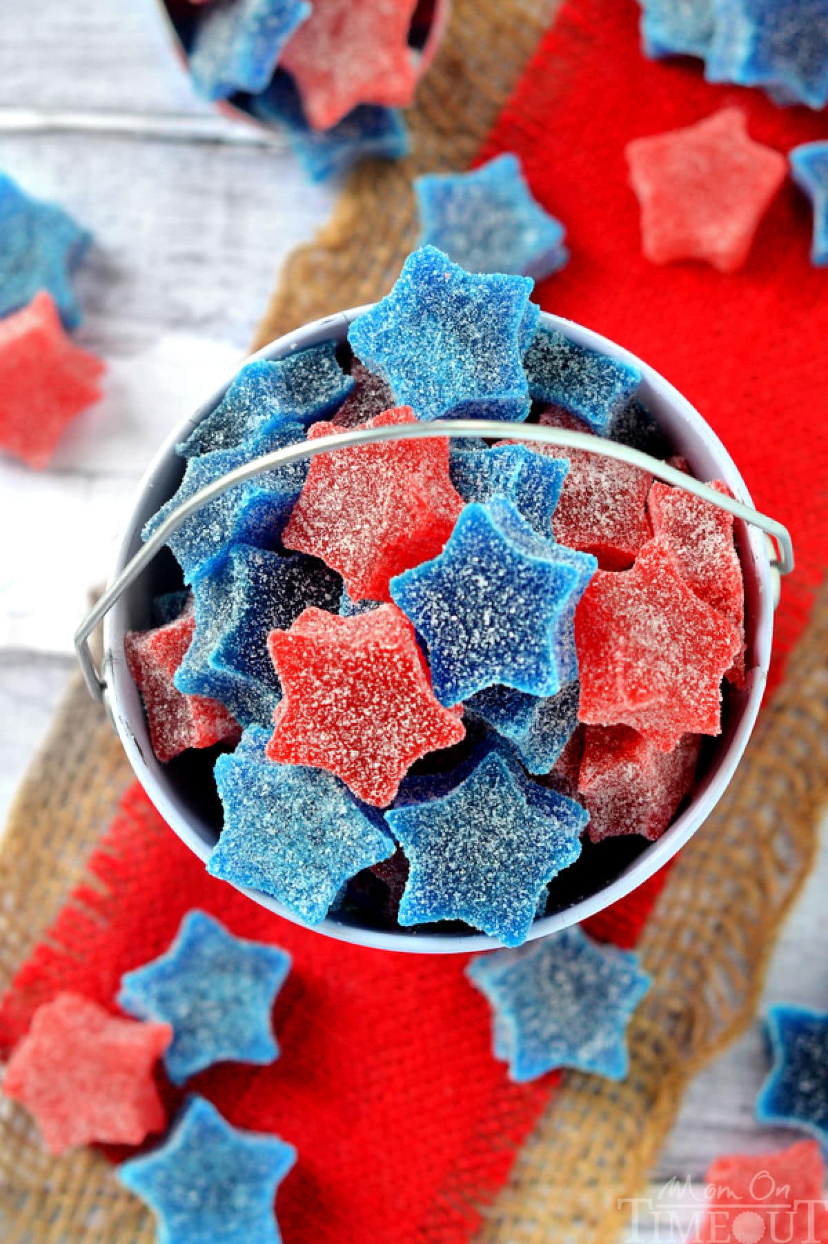 Overhead shot of red white and blue homemade gumdrops into red pail sitting on red burlap.