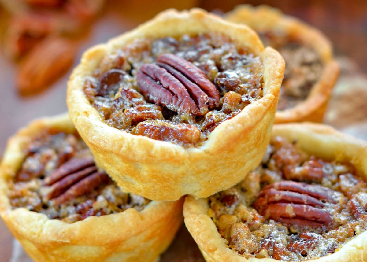 close up look at mini pecan pie with a pecan half on top.