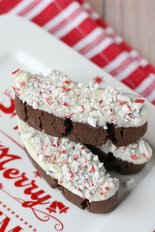 chocolate biscotti dipped in white chocolate and sprinkled with peppermint sitting on Christmas plate