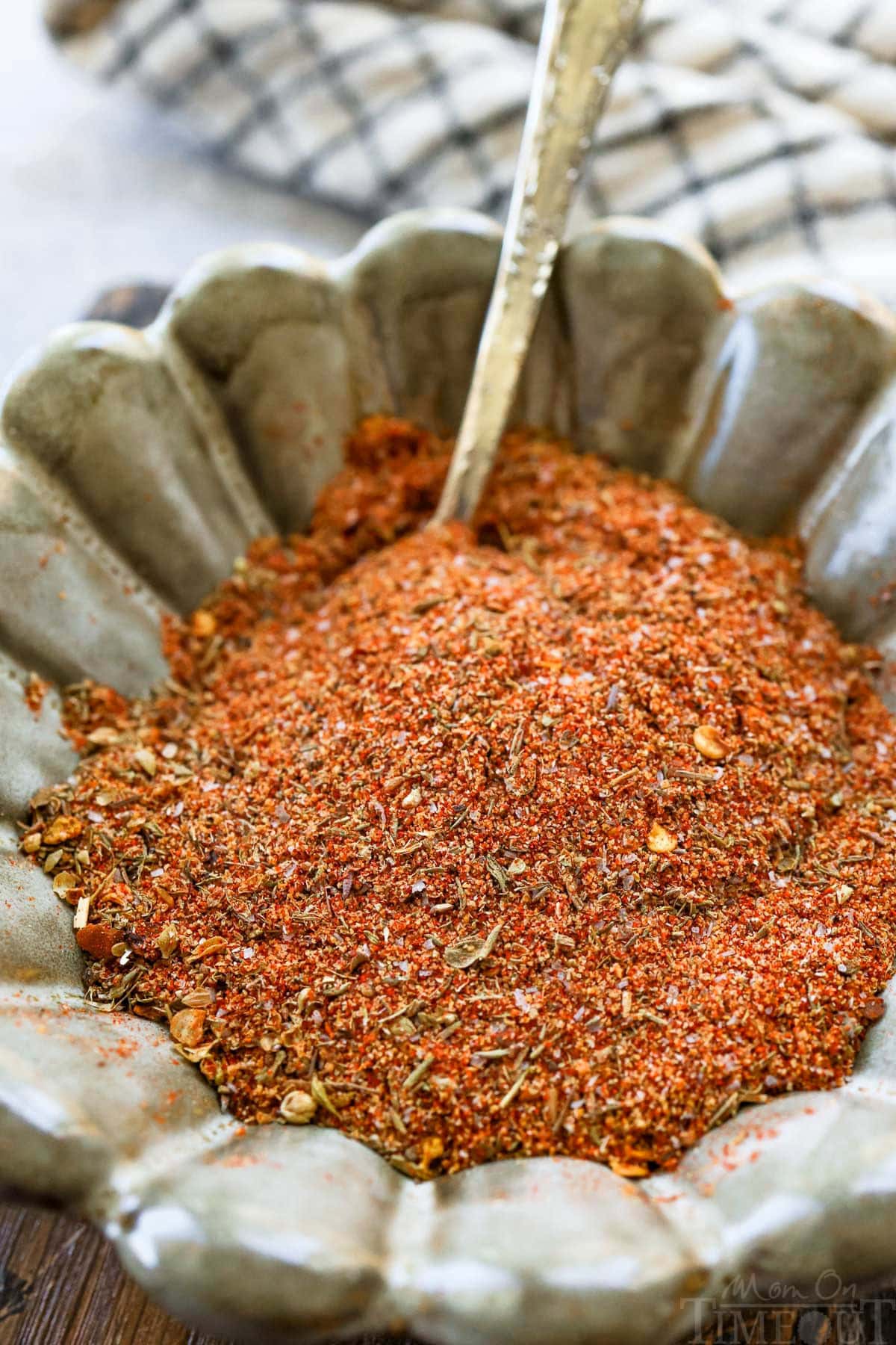 scalloped bowl filled with homemade cajun seasoning recipe. a spoon is in the bowl.