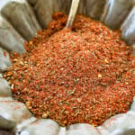 scalloped bowl filled with homemade cajun seasoning recipe. a spoon is in the bowl.