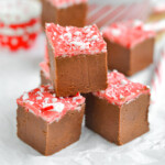 four pieces of peppermint mocha fudge stacked into a pyramid sitting on white parchment paper.