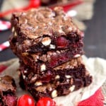 cherry chocolate brownies stacked 4 high on brown parchment with maraschino cherries on a red fork