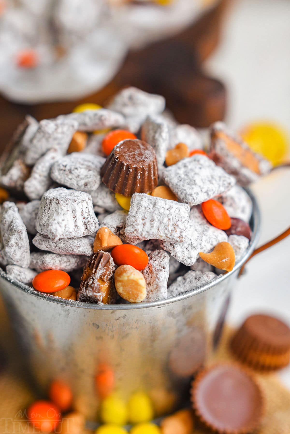 Close up, angled shot of a small metal bucket filled with muddy buddies with Reese's pieces and miniatures.