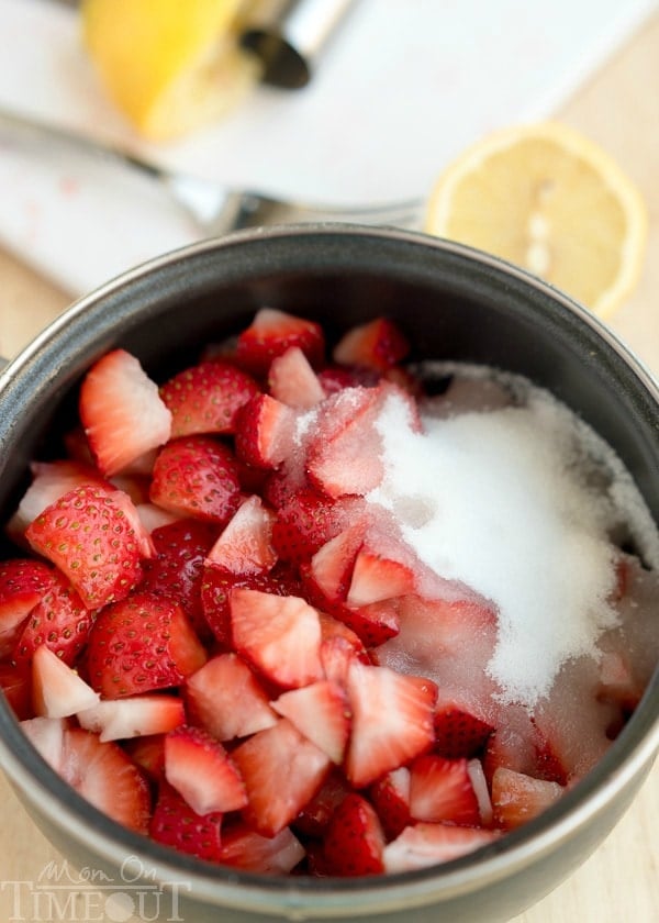 strawberry ice cream topping ingredients in a saucepan including strawberries and sugar and lemon juice