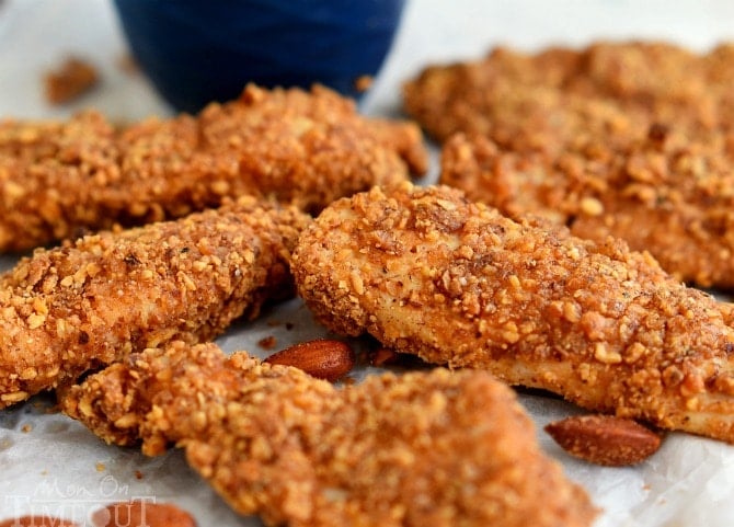 cooked chicken strips on parchment with almonds scattered about