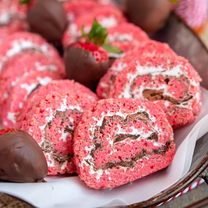Metal tray filled with strawberry and chocolate rice krispie treat pinwheels along with chocolate covered strawberries.