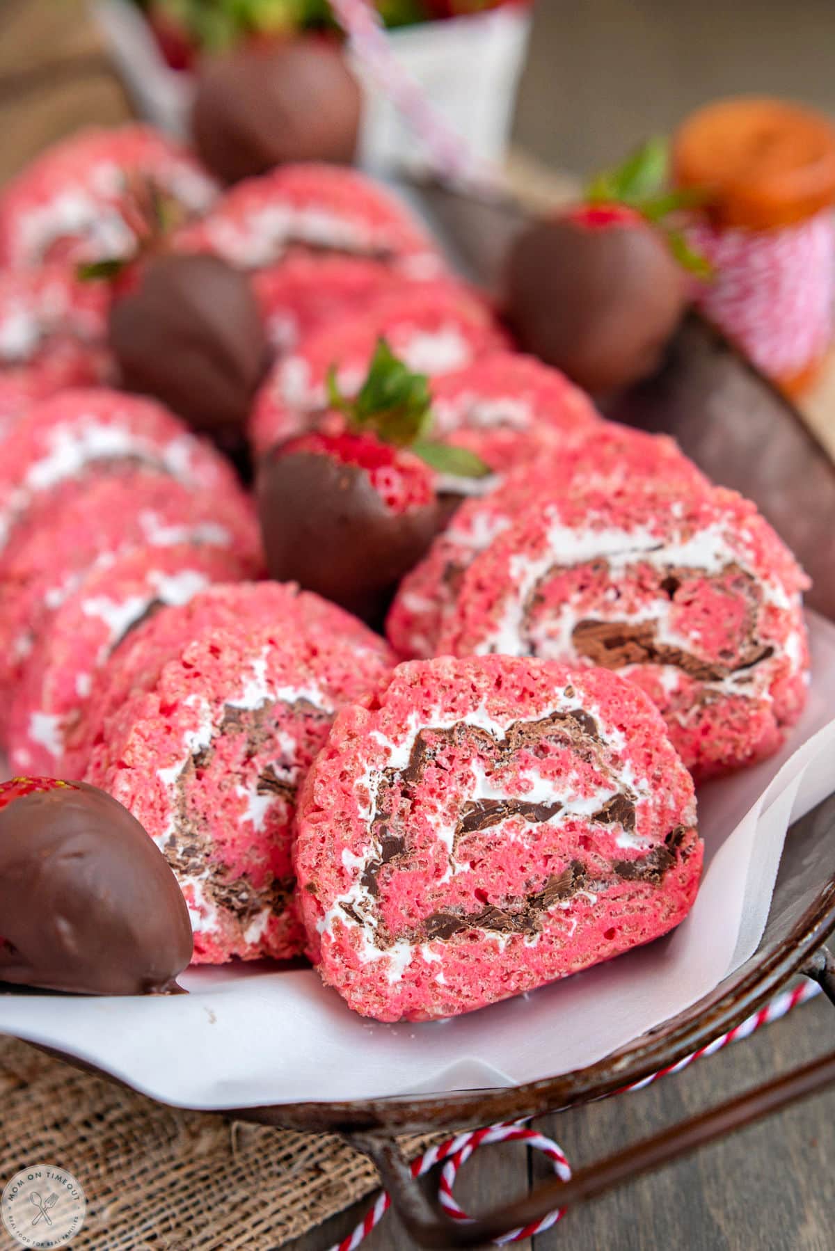 Metal tray filled with strawberry and chocolate rice krispie treat pinwheels along with chocolate covered strawberries.