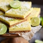 key lime pie bars sitting in a pile on a wooden stand.