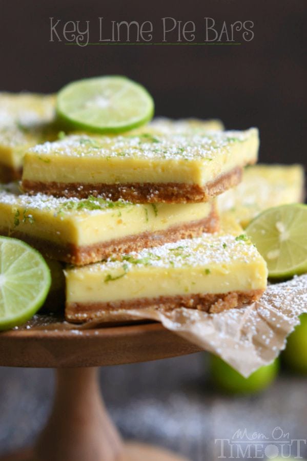 key lime pie bars stacked on a cake stand with lime slices