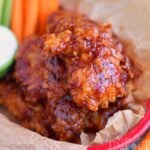 chicken strips with honey barbecue sauce in red plastic basket with carrots and celery sticks.