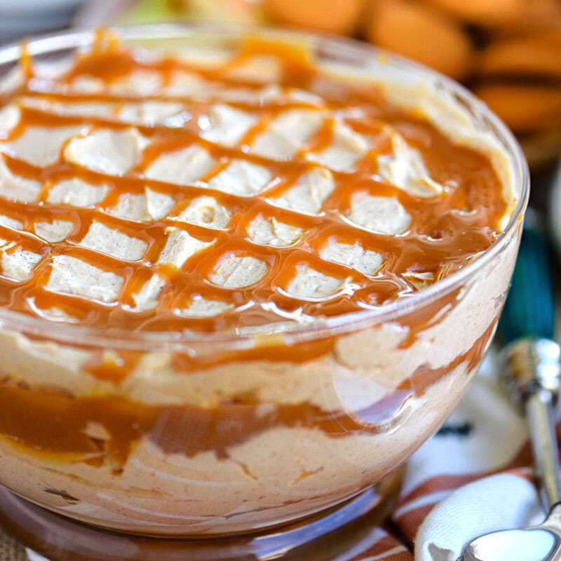 Pumpkin cheesecake dip in glass bowl with swirls of caramel sauce.