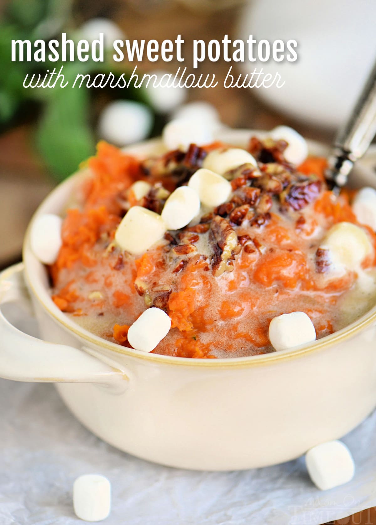 mashed sweet potatoes topped with marshmallows and pecans in beige bowl with text overlay at top of image