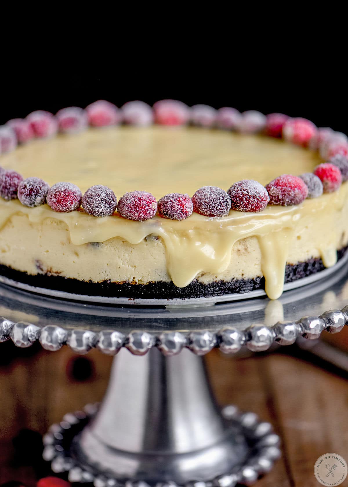 Close up shot of white chocolate cheese with cranberries on cake stand.