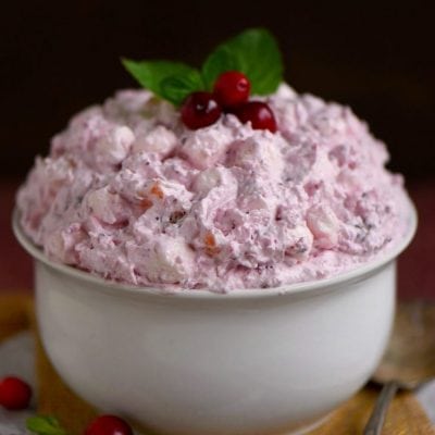 cranberry fluff in a large white bowl topped with fresh cranberries and mint and title overlay at top