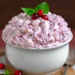 cranberry fluff in a large white bowl topped with fresh cranberries and mint