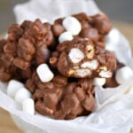 white bowl full of rocky road peanut clusters with one cut in half. marhsmallows are scattered on top.