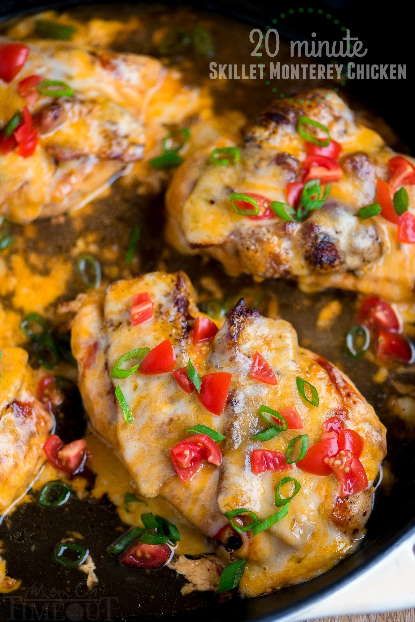 close up of monterey chicken in skillet topped with tomatoes and green onions