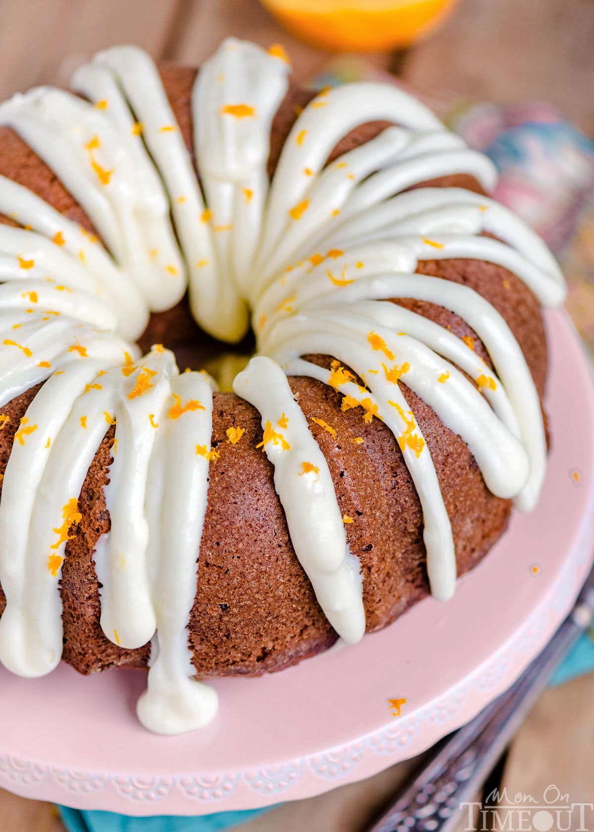top down angled look at cream cheese frosting on hummingbird bundt cake topped with orange zest.