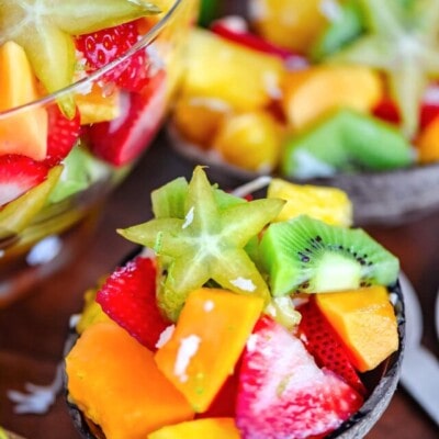 coconut half filled with tropical fruit salad. very brightly colored fruits.