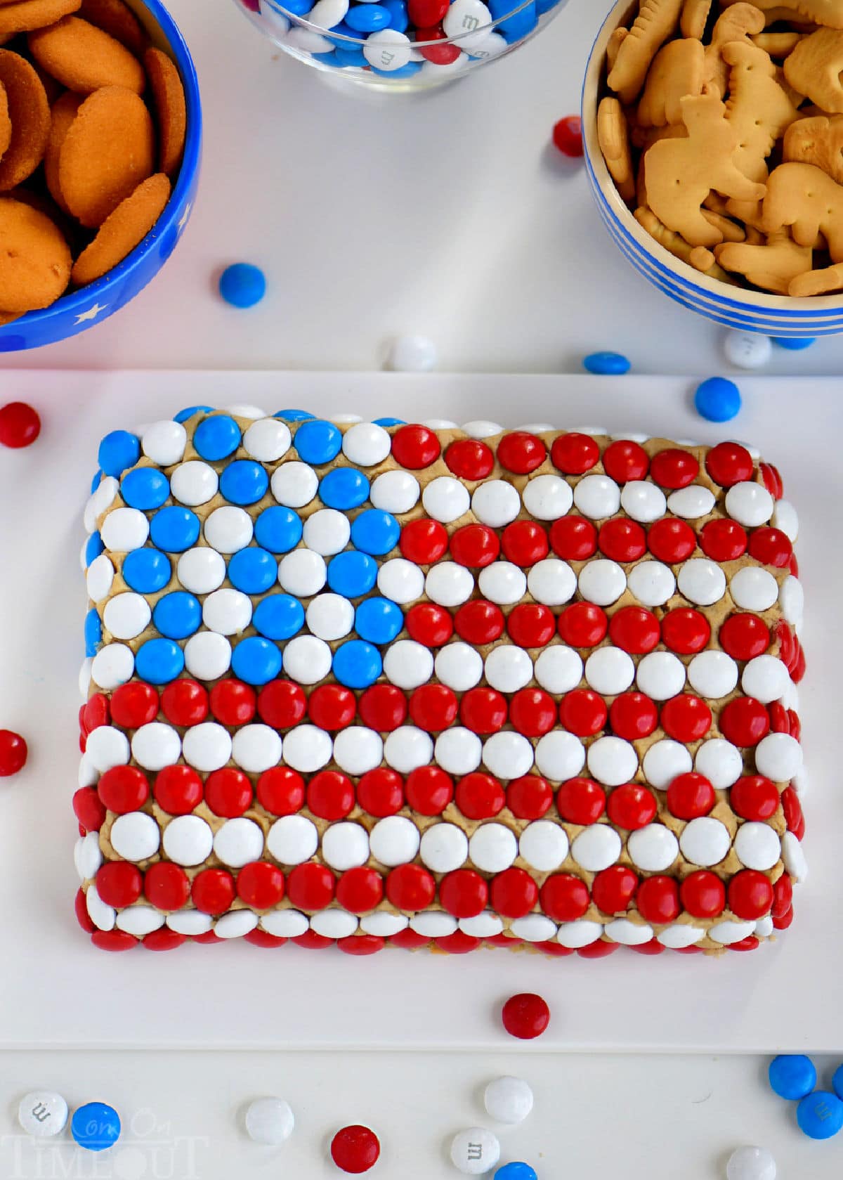 Overhead shot of chocolate chip cookie dip on white board decorated to look like the US flag with MMs.