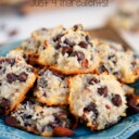 almond joy cookies piles high on a blue plate with title overlay at top