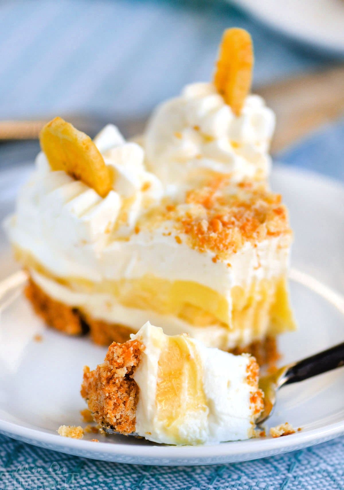 Slice of no bake banana pudding cheesecake recipe on plate with a bite removed with a fork.