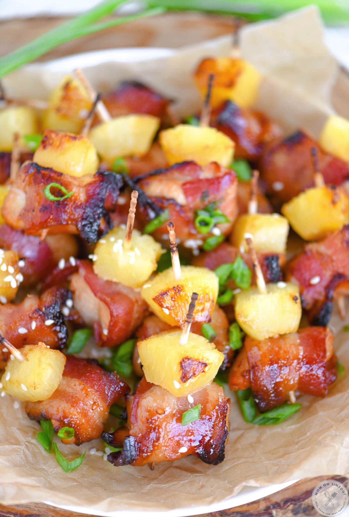 Overhead shot of bacon chicken teriyaki bites on white round plate lined with parchment.